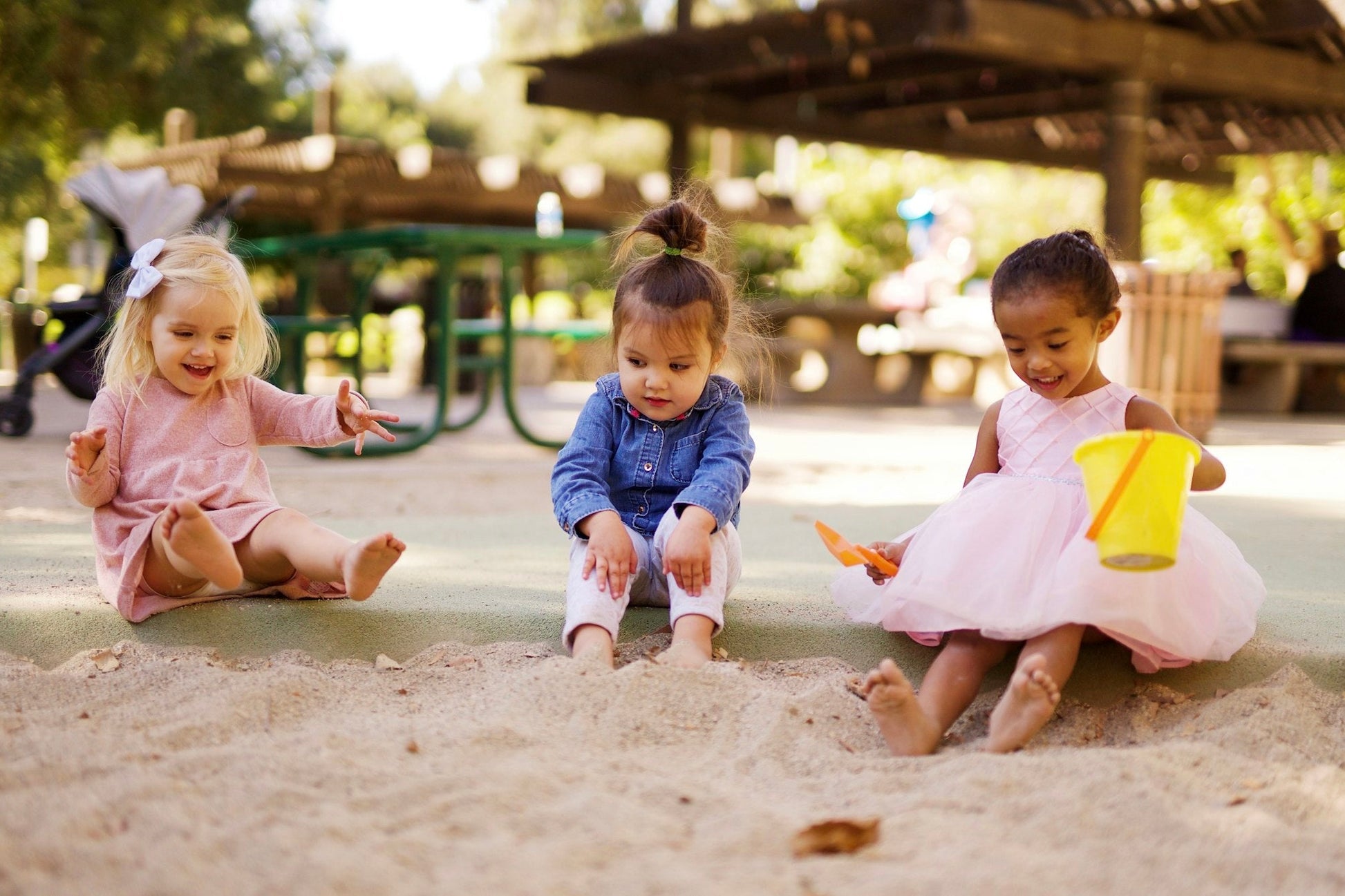 Three toddlers playing side by side in a sandpit