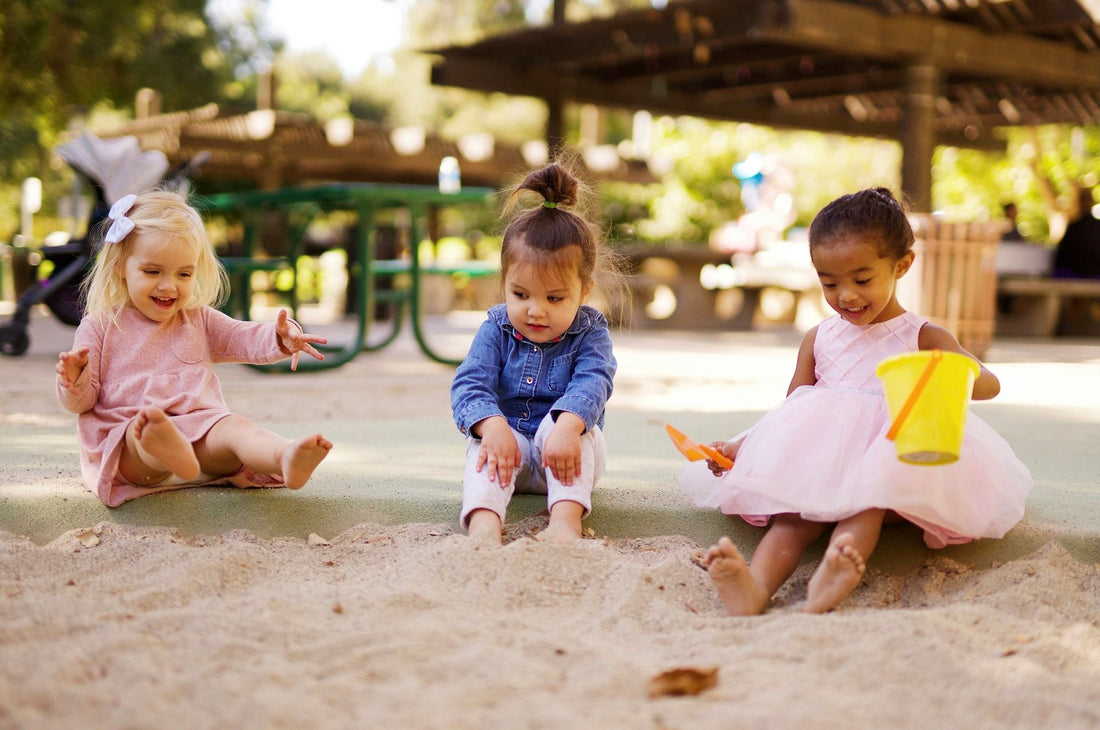 Three toddlers playing side by side in a sandpit
