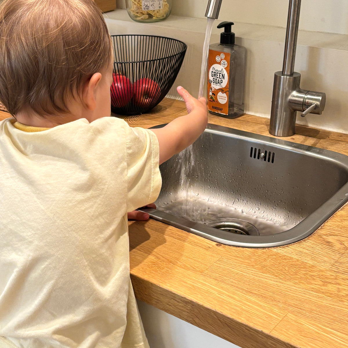 Un tout-petit qui se lave les mains dans le lavabo avant le goûter